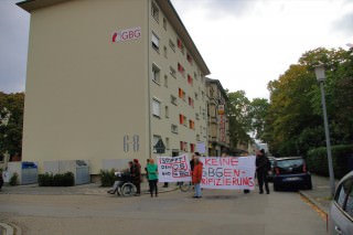 Wie ein Damoklesschwert hängt das GBG-Logo über den demonstrierenden Mietern | Foto: M. Schülke