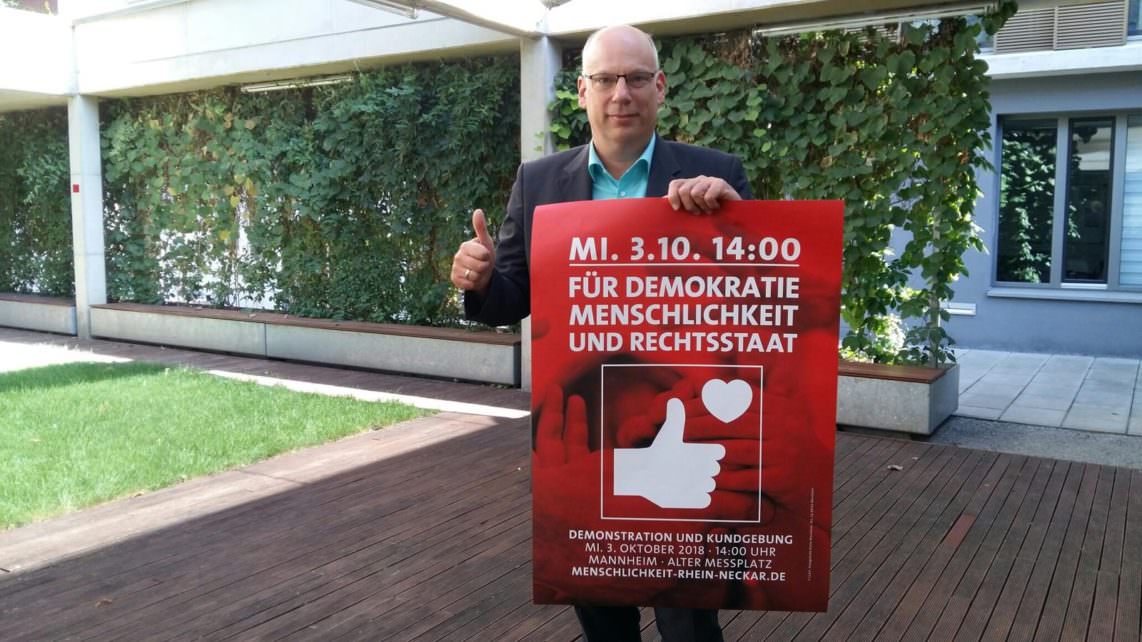 Dekan Ralph Hartmann mit dem Plakat der Veranstaltung am 3. Oktober: 