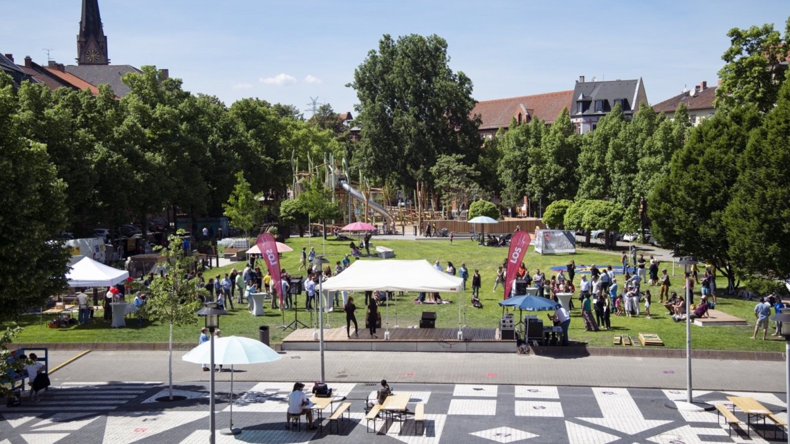 Im Vordergrund die multifunktionale Bühne mit ihrer charakteristischen Bodenbemalung, links die Urban-Gardening-Fläche, in der Mitte die frisch angelegte Rasenfläche mit Sitzgelegenheiten, hinten der komplett neu gestaltete Kinderspielplatz | Foto: MWSP / Annette Mück